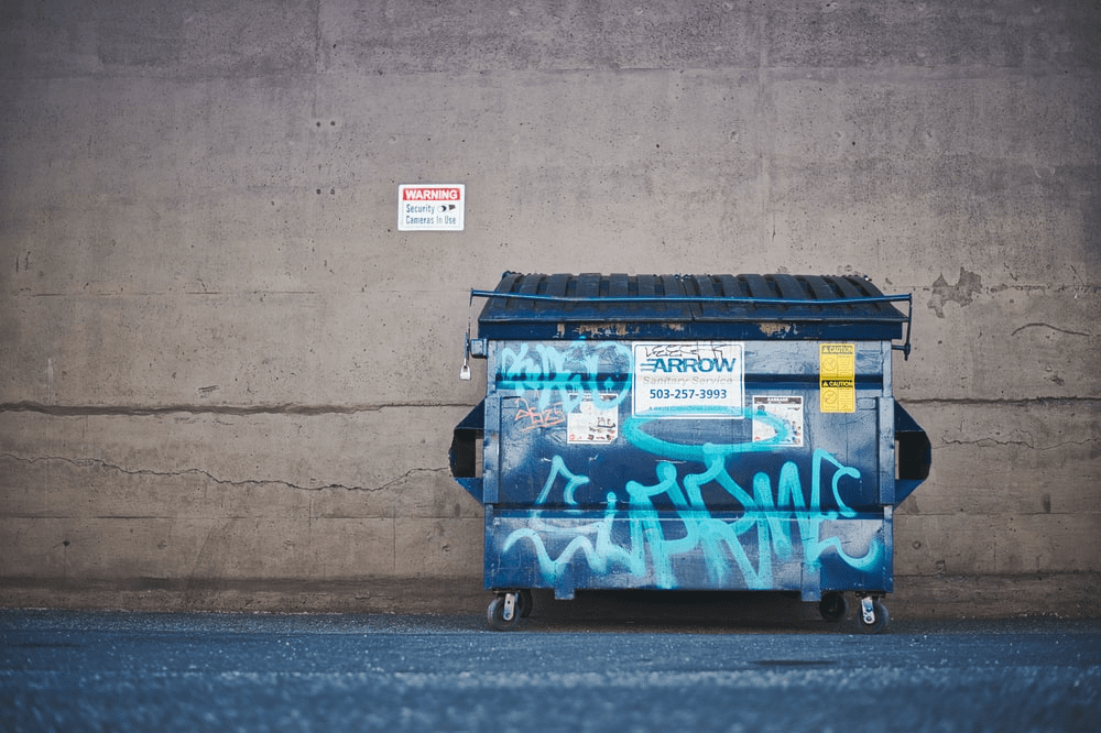 A dumpster against a wall.