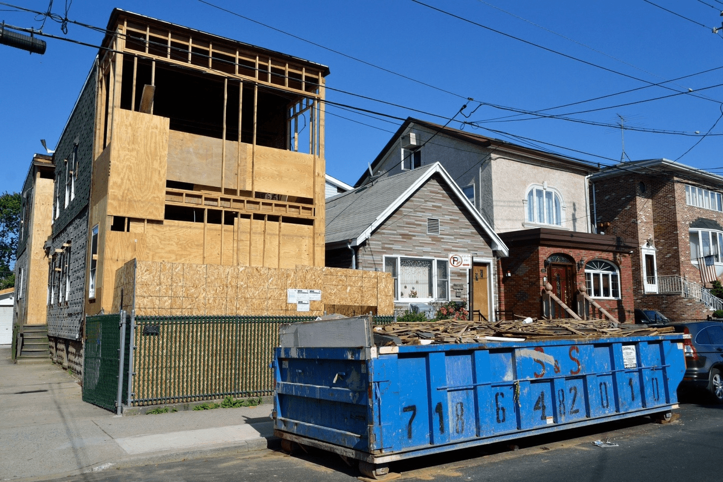 Blue dumpster in front house under construction